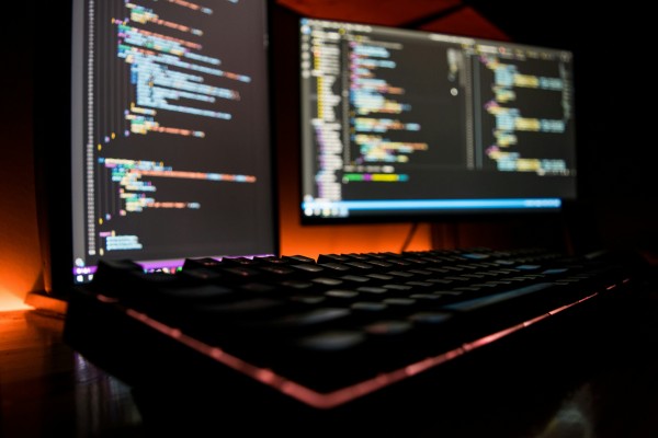 Keyboard and monitors showing code